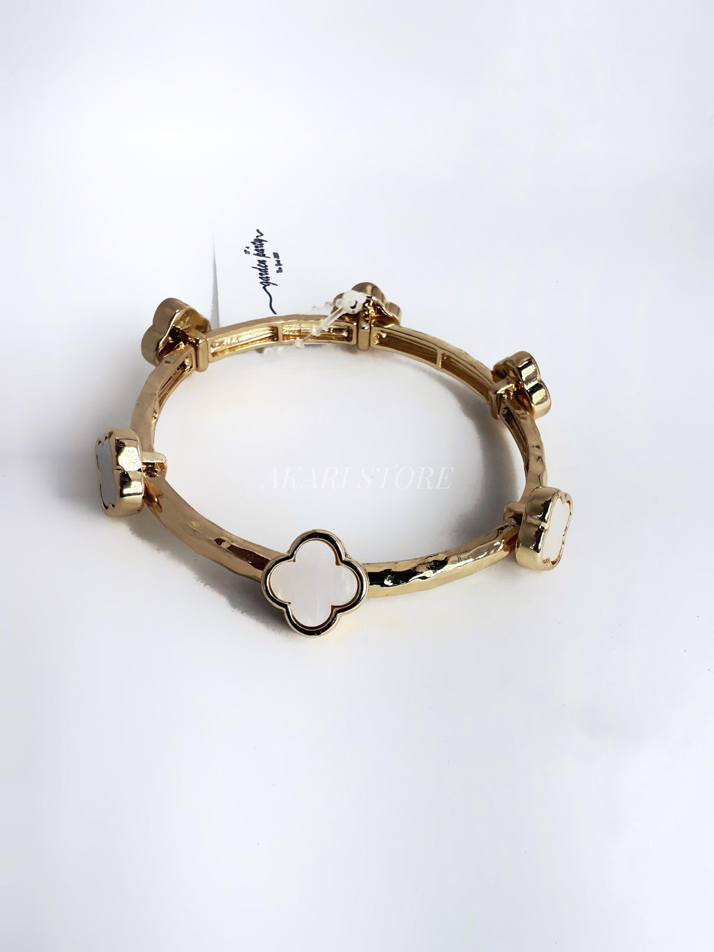 Brazalete dorado con dijes de trébol blanco