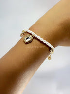 Pulsera  de perlas blancas con dijes dorados