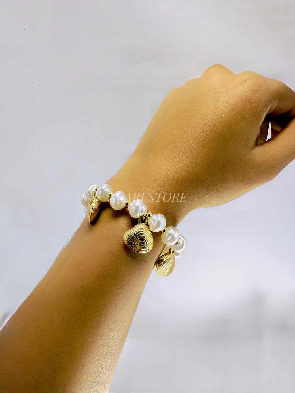 Pulsera dorada con dijes de conchas y perlas