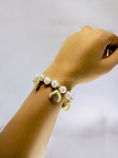 Pulsera dorada con dijes de conchas y perlas